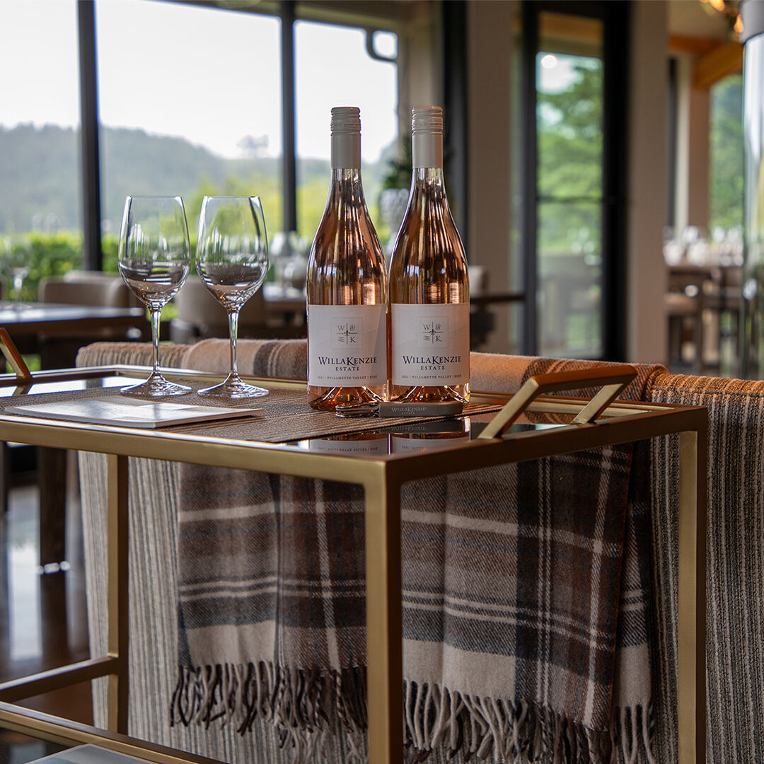 Two glasses and 2 bottles of rosé sitting on a bar in the WillaKenzie Tasting room.