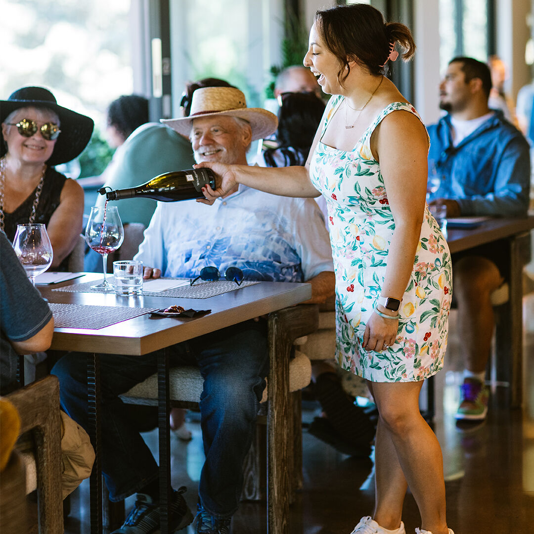 Sydney McMurry pouring bottle for guests in tasting room.